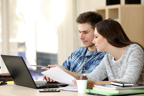 Studierende sitzen vor dem Laptop und diskutieren