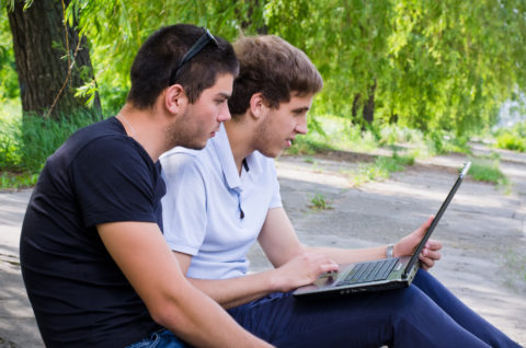 Studenten sitzen mit Laptop in Park